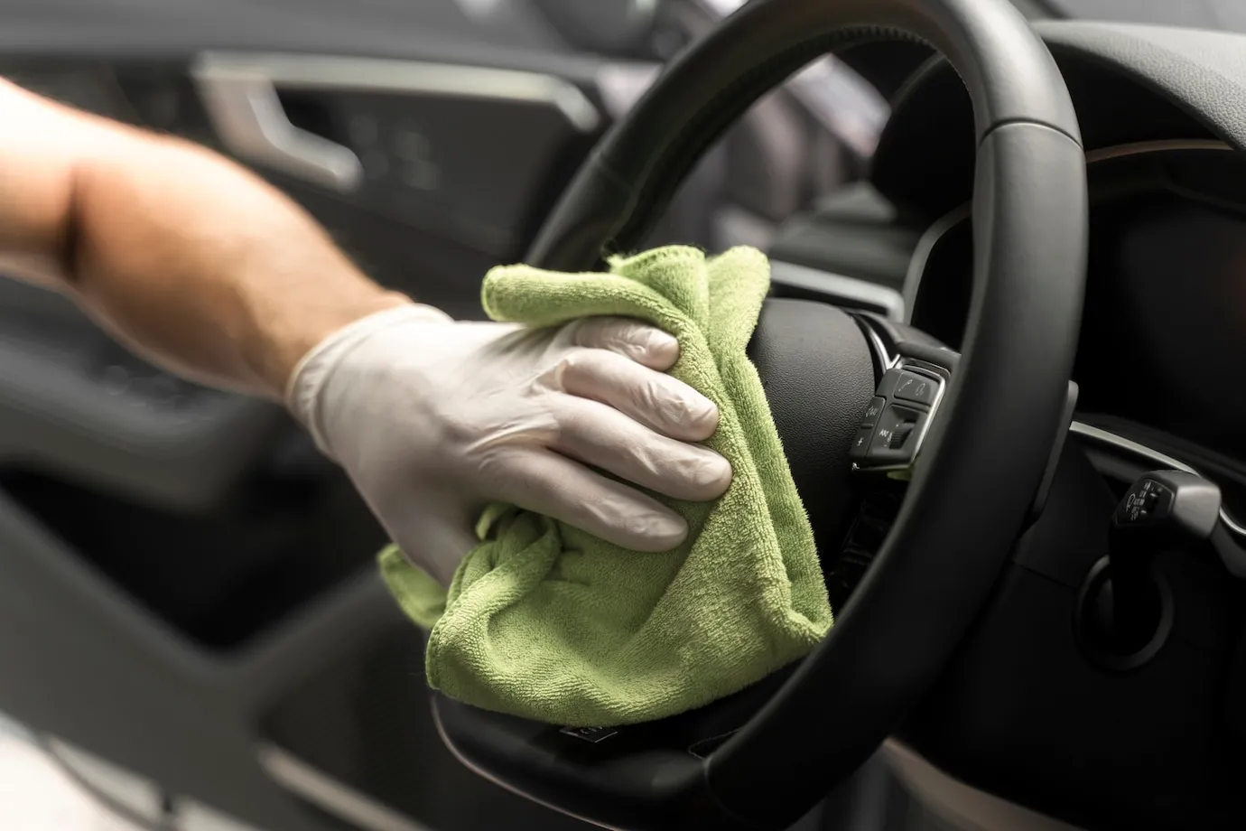 limpeza-interior-do-carro-processo-de-limpeza-de-veiculo-mao-com-luva-e-uma-flanela-limpando-volante-de-carro